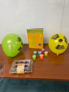 table with glow in the dark slimes and cupcakes, and a book about Marie Curie